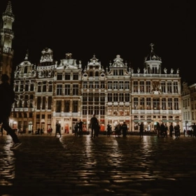 Vue nocturne de la Grand-Place de Bruxelles illuminée se reflétant sur les pavés mouillés, illustrant la zone d'intervention pour la réparation de toiture.