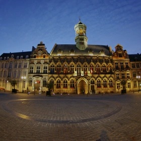 L'Hôtel de Ville de Mons et la Grand-Place illuminés de nuit sous un ciel crépusculaire.